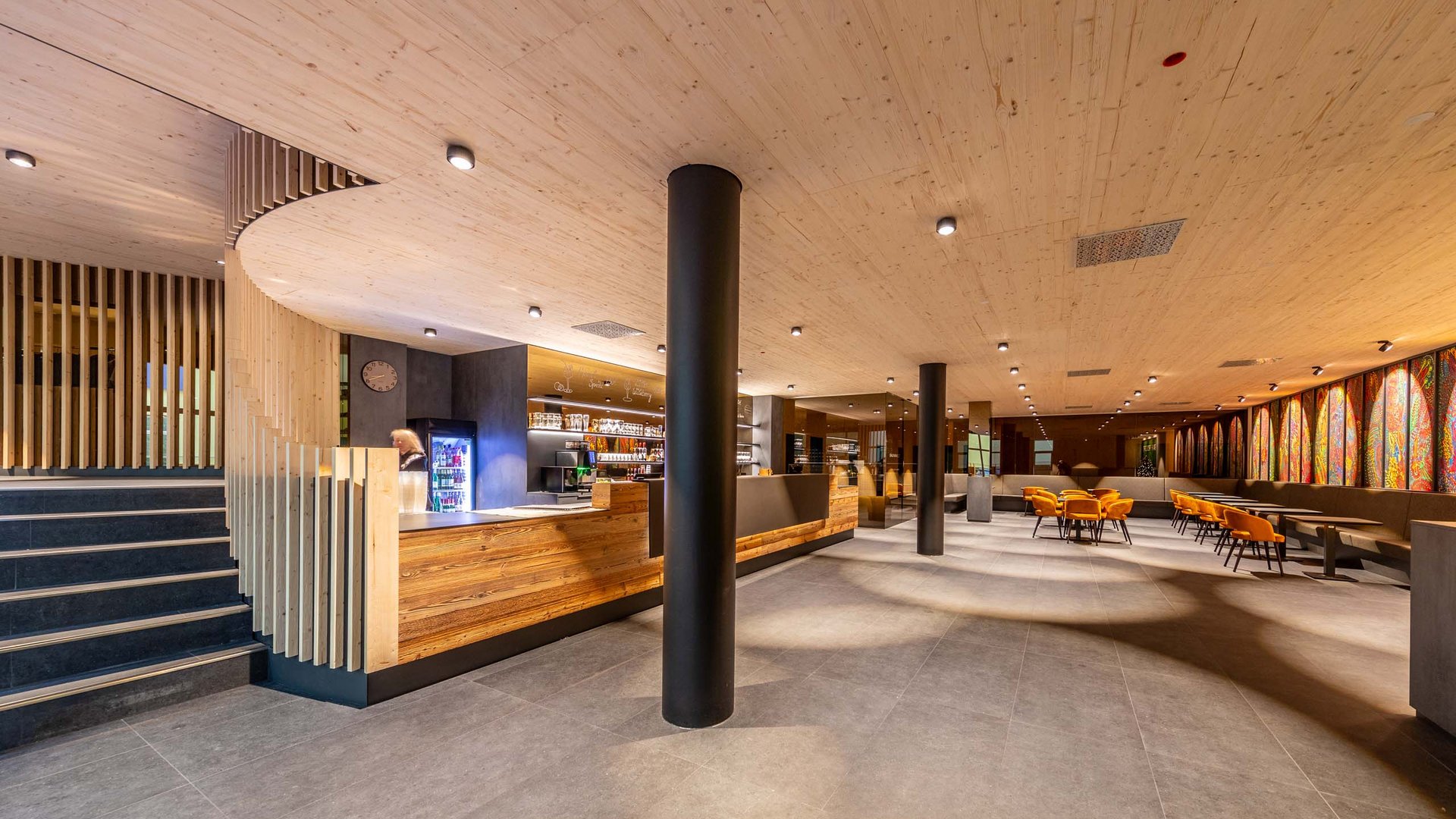 Modern restaurant interior with wooden counter and orange chairs