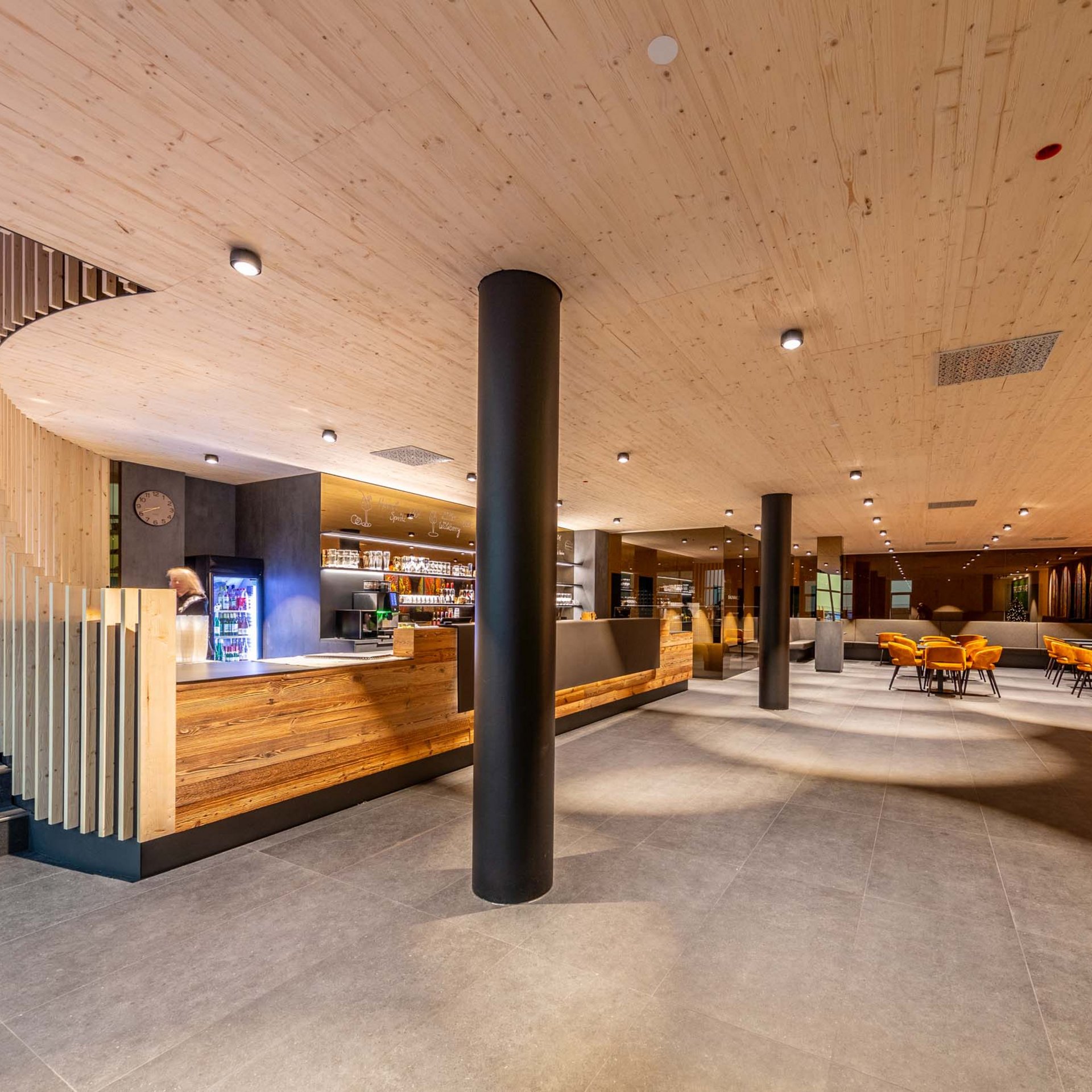 Moderner Restaurantinnenraum mit Holztresen und orangen Stühlen