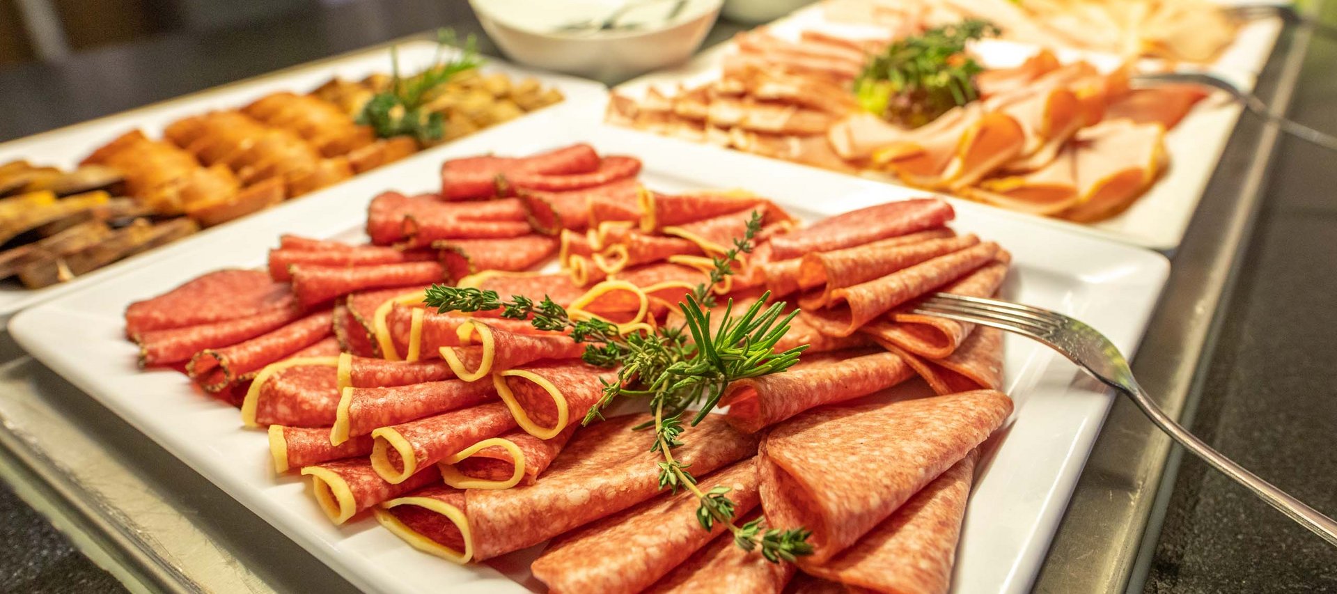 Ein Hotel in Jena mit All-inclusive-Verpflegung Verschiedene Wurst- und Aufschnittplatten mit Kräutern auf einem Buffet
