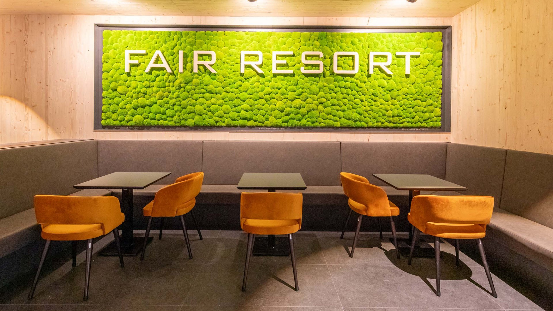 Modern seating area with orange chairs and green FAIR RESORT sign on the wall