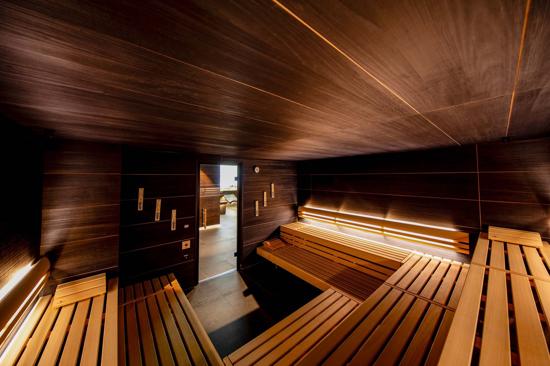 Innenansicht einer modernen Holzsauna mit Sitzbänken und indirekter Beleuchtung