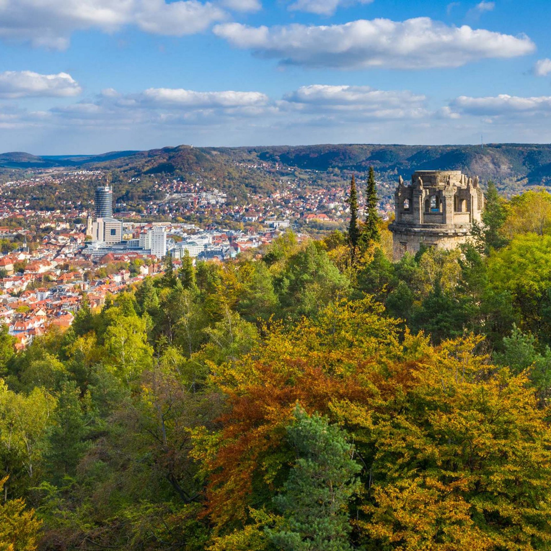 View of a city with autumn trees and a historic tower on a hill