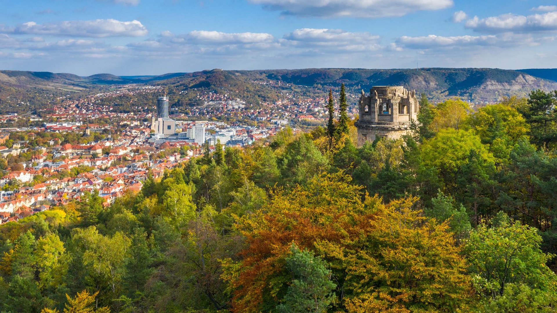 View of a city with autumn trees and a historic tower on a hill