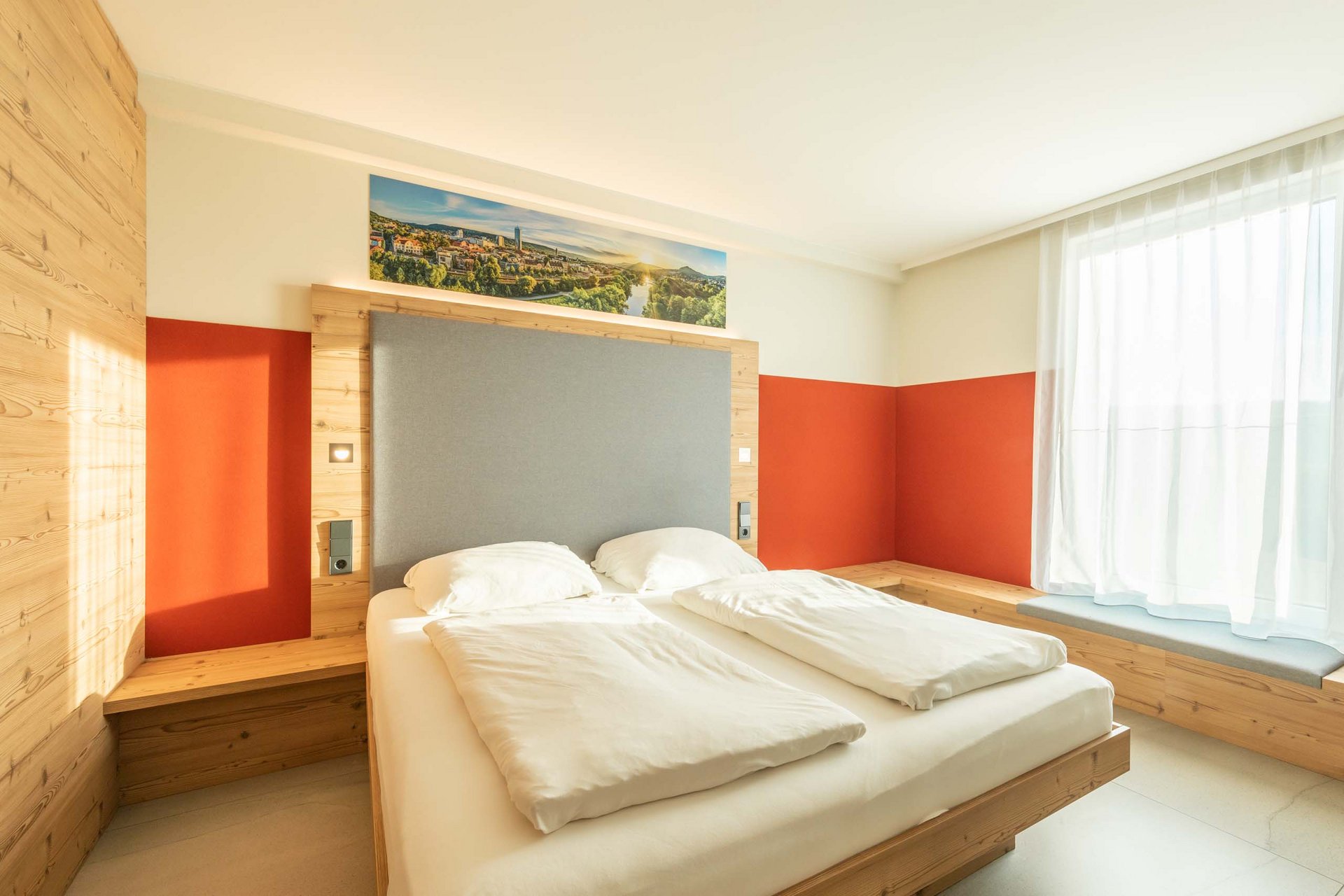 Modernes Schlafzimmer mit Doppelbett, Holzvertäfelung und großem Fenster mit Vorhang