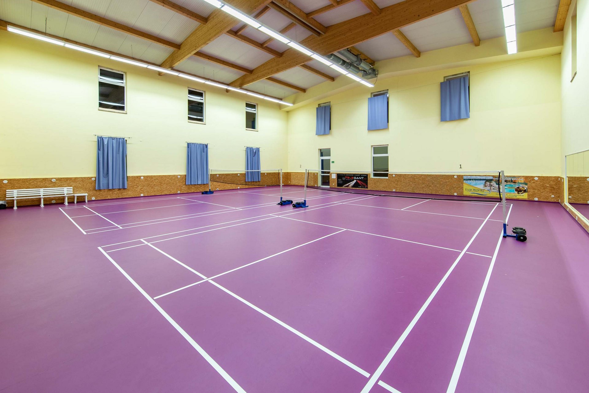 Leerer Badminton-Spielfeldboden mit violettem Belag in einer Halle