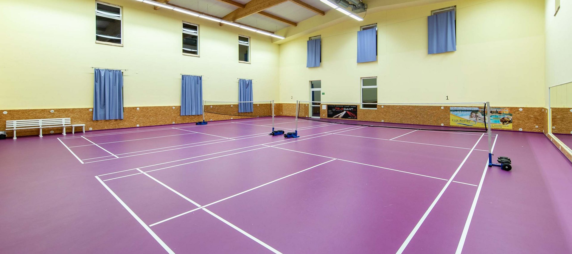Leerer Badminton-Spielfeldboden mit violettem Belag in einer Halle