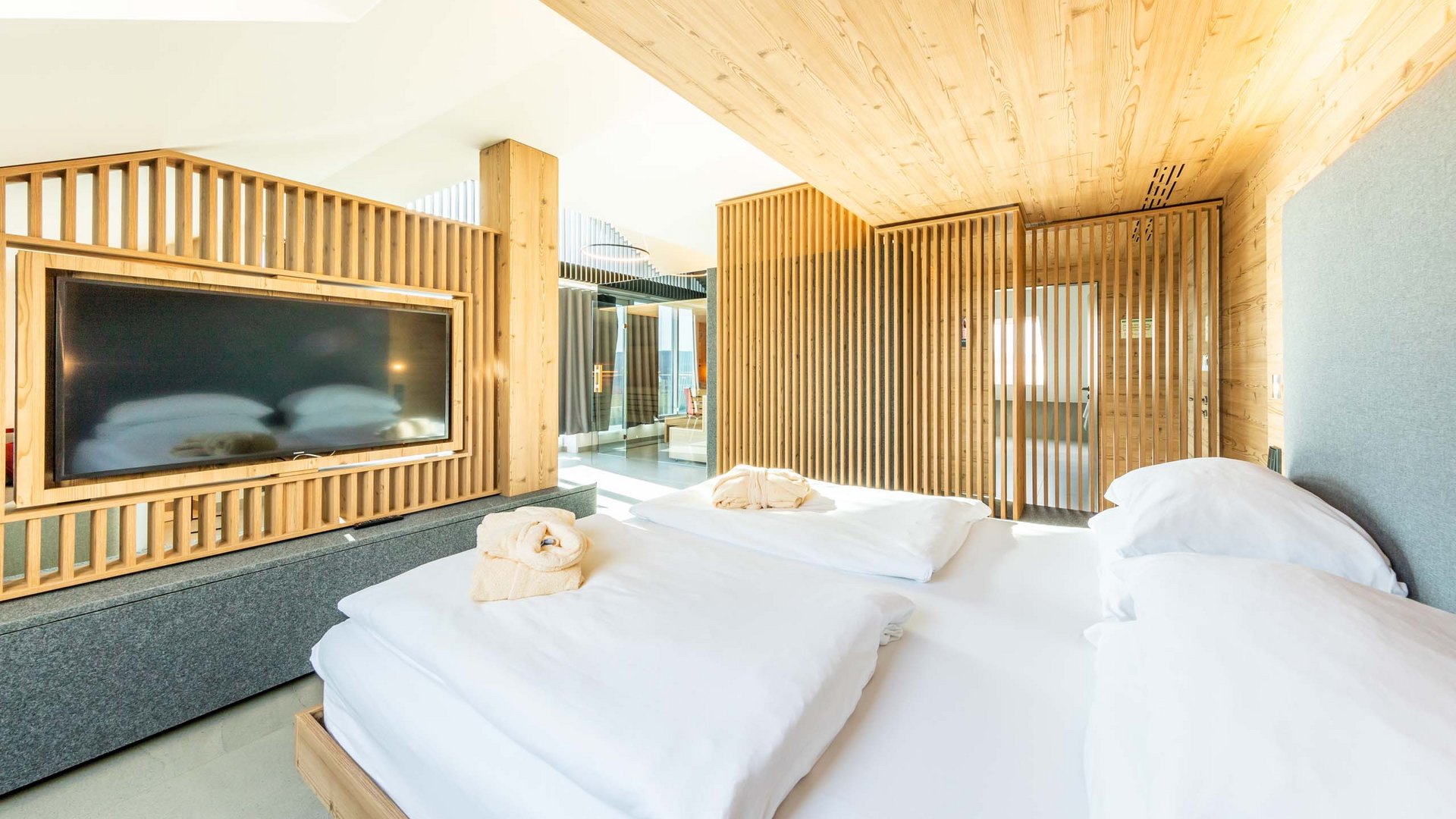 Helles Schlafzimmer mit Holzverkleidungen und großem Fernseher