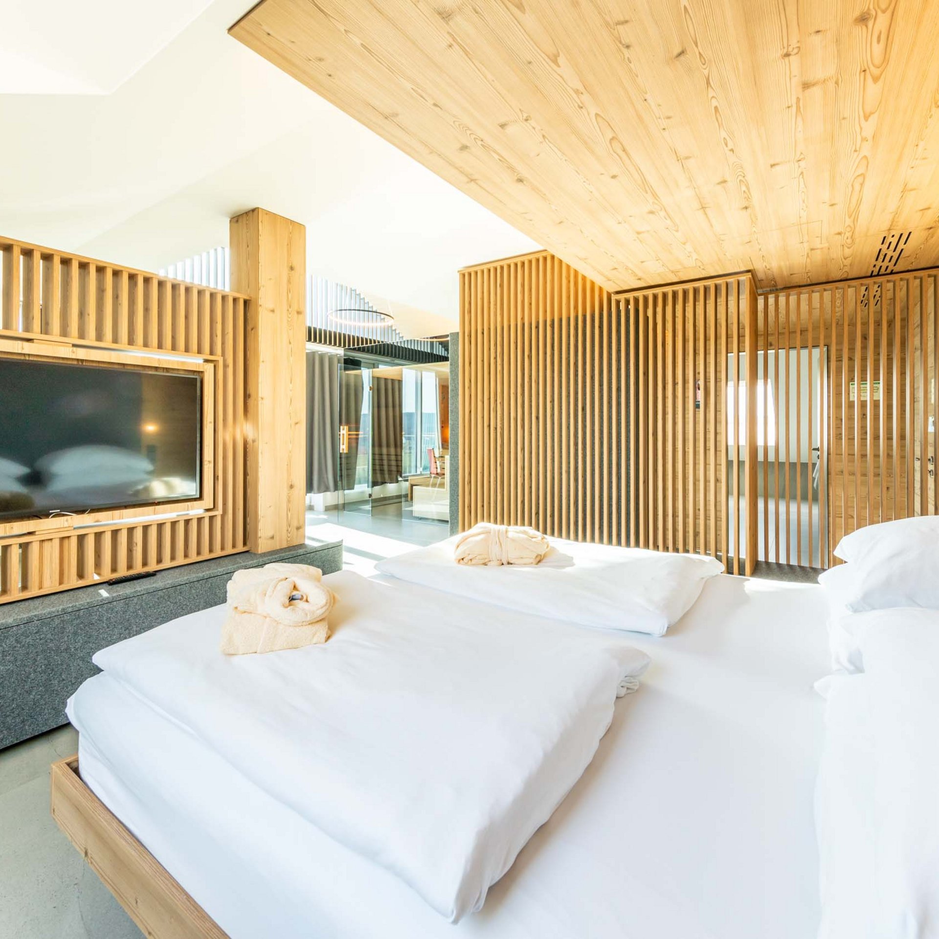 Helles Schlafzimmer mit Holzverkleidungen und großem Fernseher