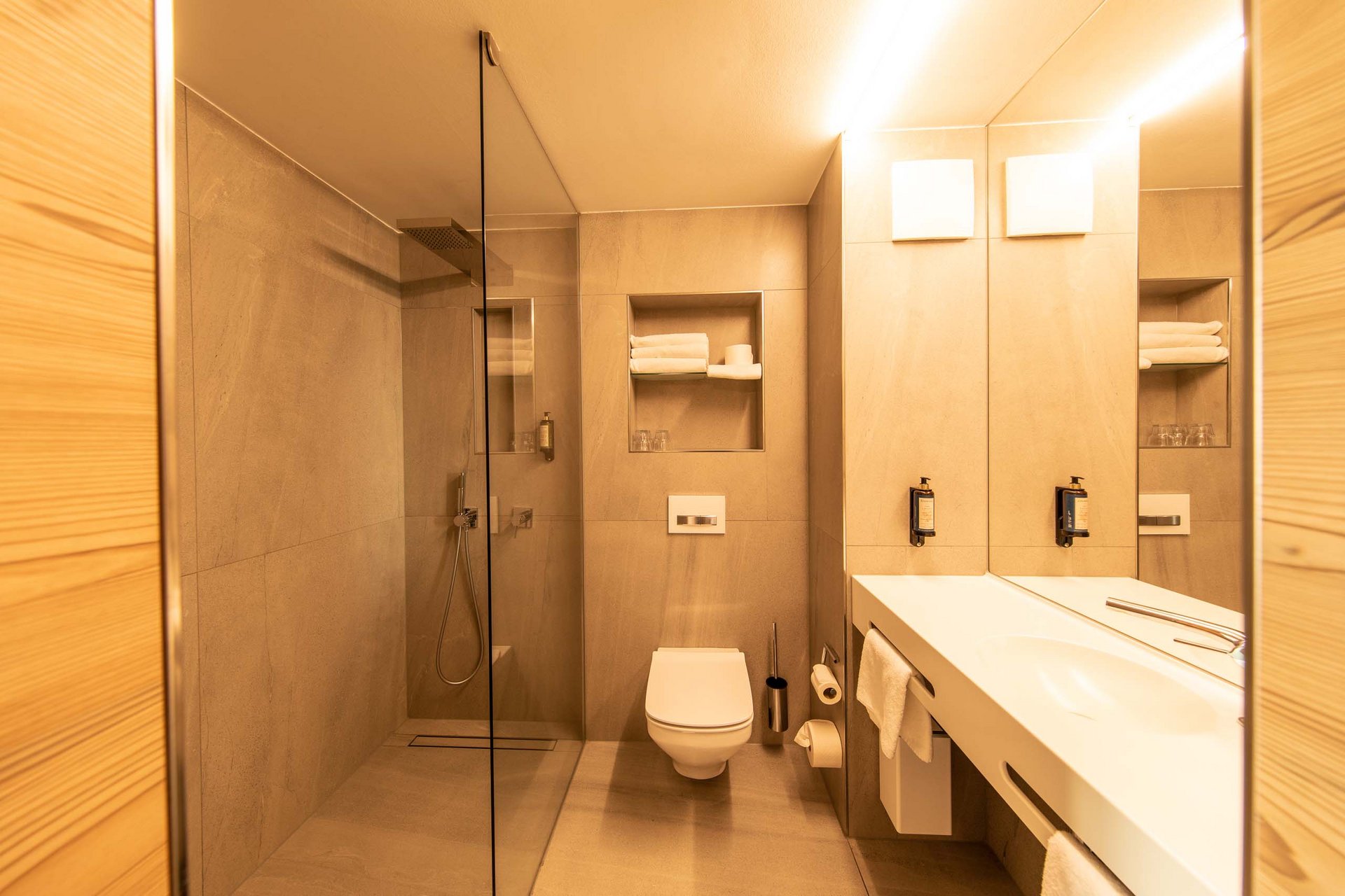 Modernes Badezimmer mit Dusche, Toilette und Waschbecken in warmen Tönen