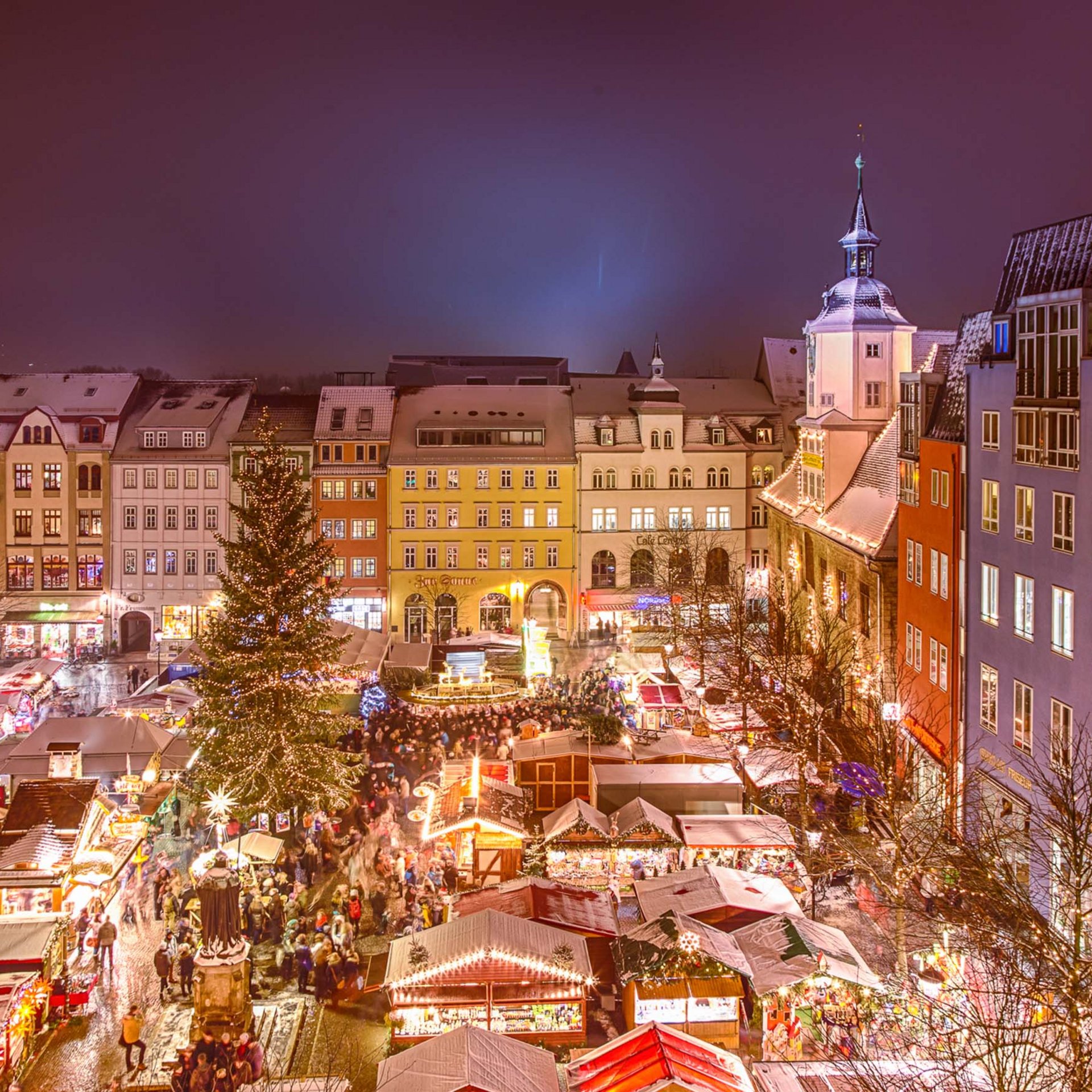 Evening Christmas market with lit tree and historic buildings