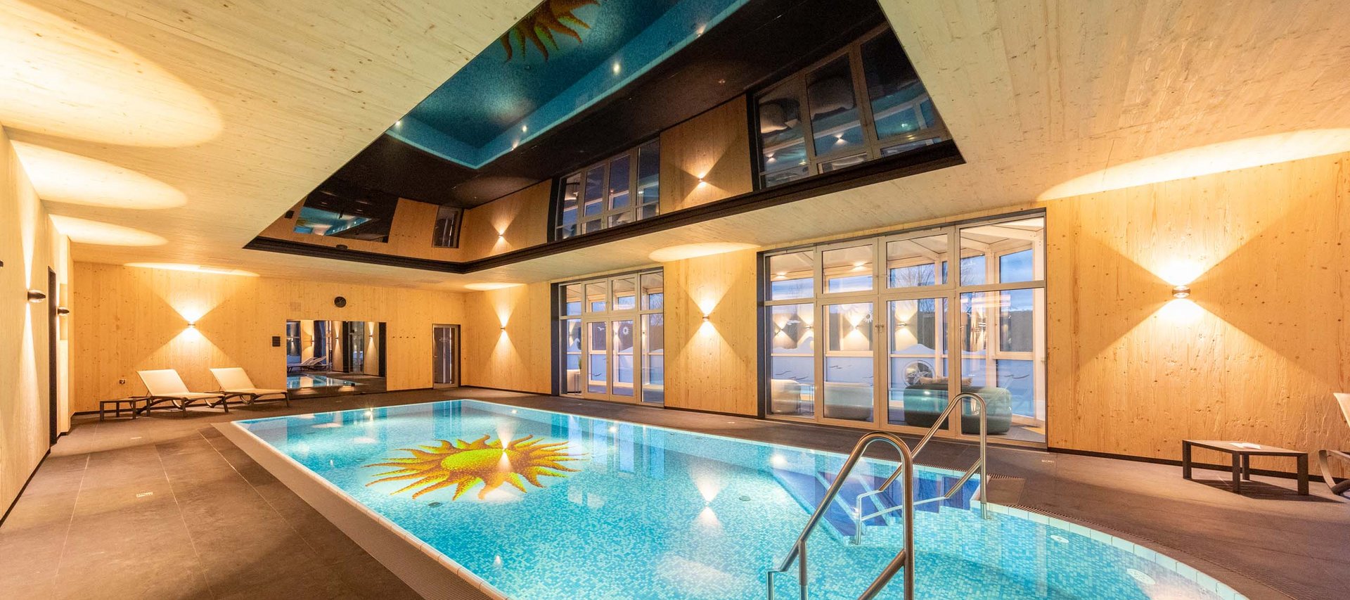 Day Spa in Jena: ein Tag nur für Sie Innenpool mit Holzverkleidung, Lounge-Stühlen und beleuchtetem Schwimmbecken