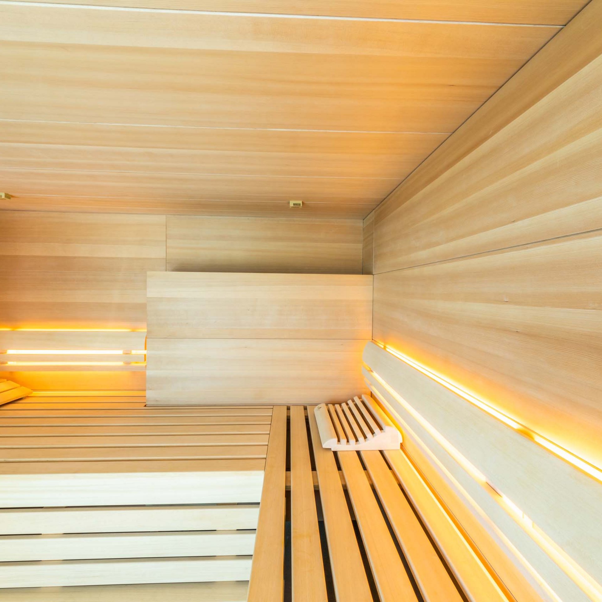 Innenraum einer modernen Sauna mit Holzverkleidung und warmem Licht