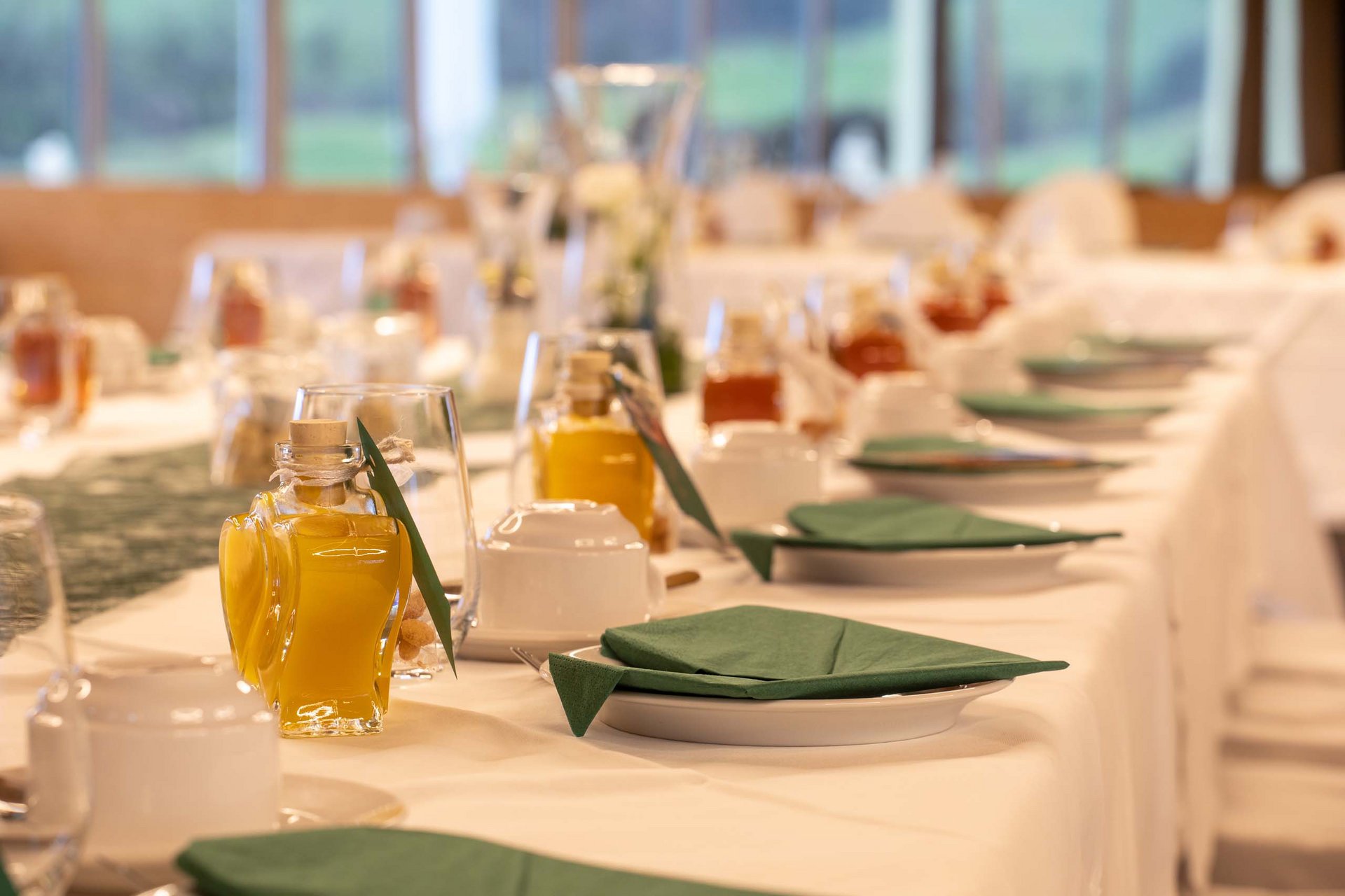 Festively set table with green napkins and small bottles of yellow liquid