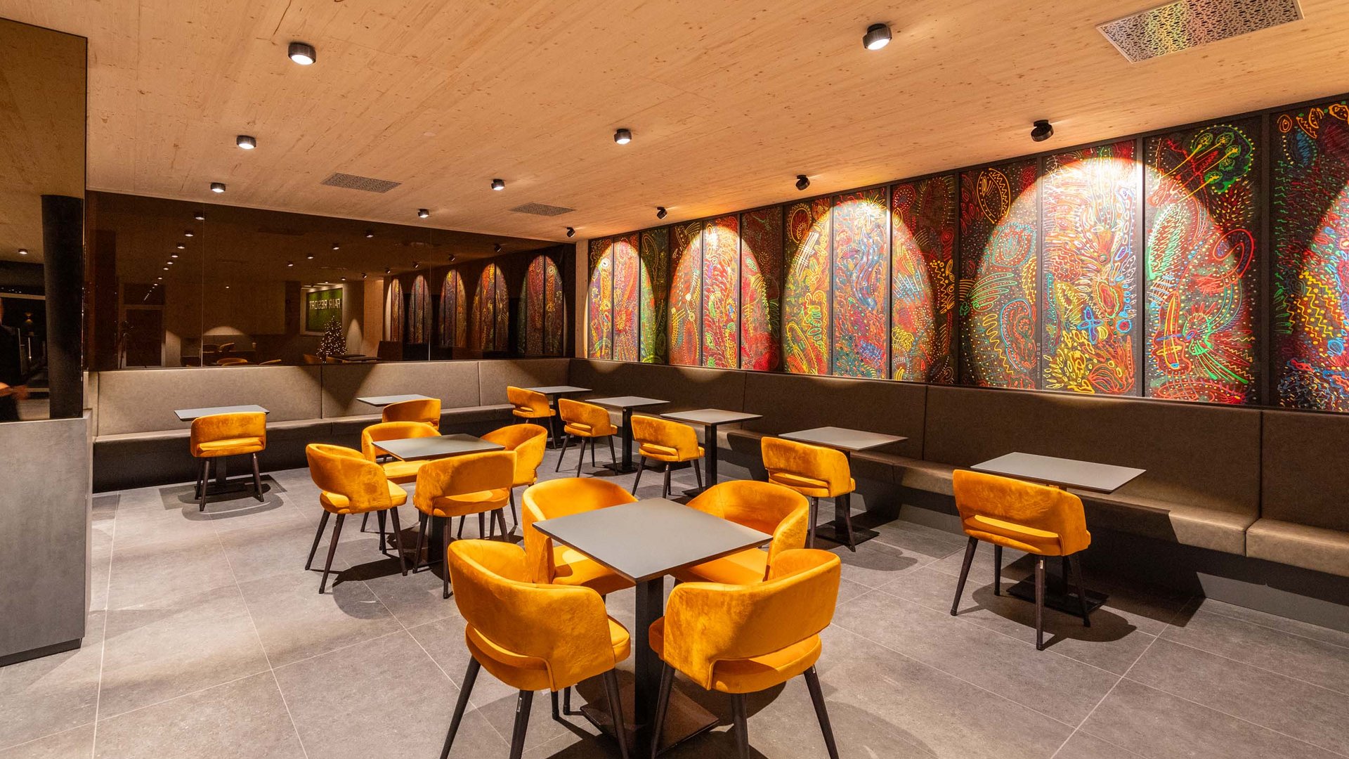 Modern seating area with orange chairs and colorful wall art in cozy venue
