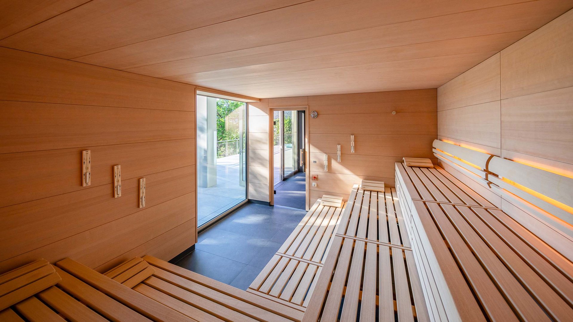 Interior of modern Finnish sauna with wooden benches and terrace access