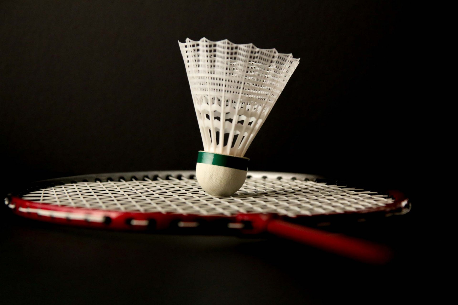 Badmintonschläger mit Federball vor schwarzem Hintergrund