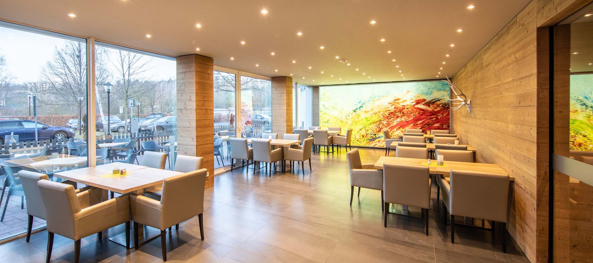 Modernes Restaurant mit Stühlen, Tischen und großen Fenstern mit Außenblick