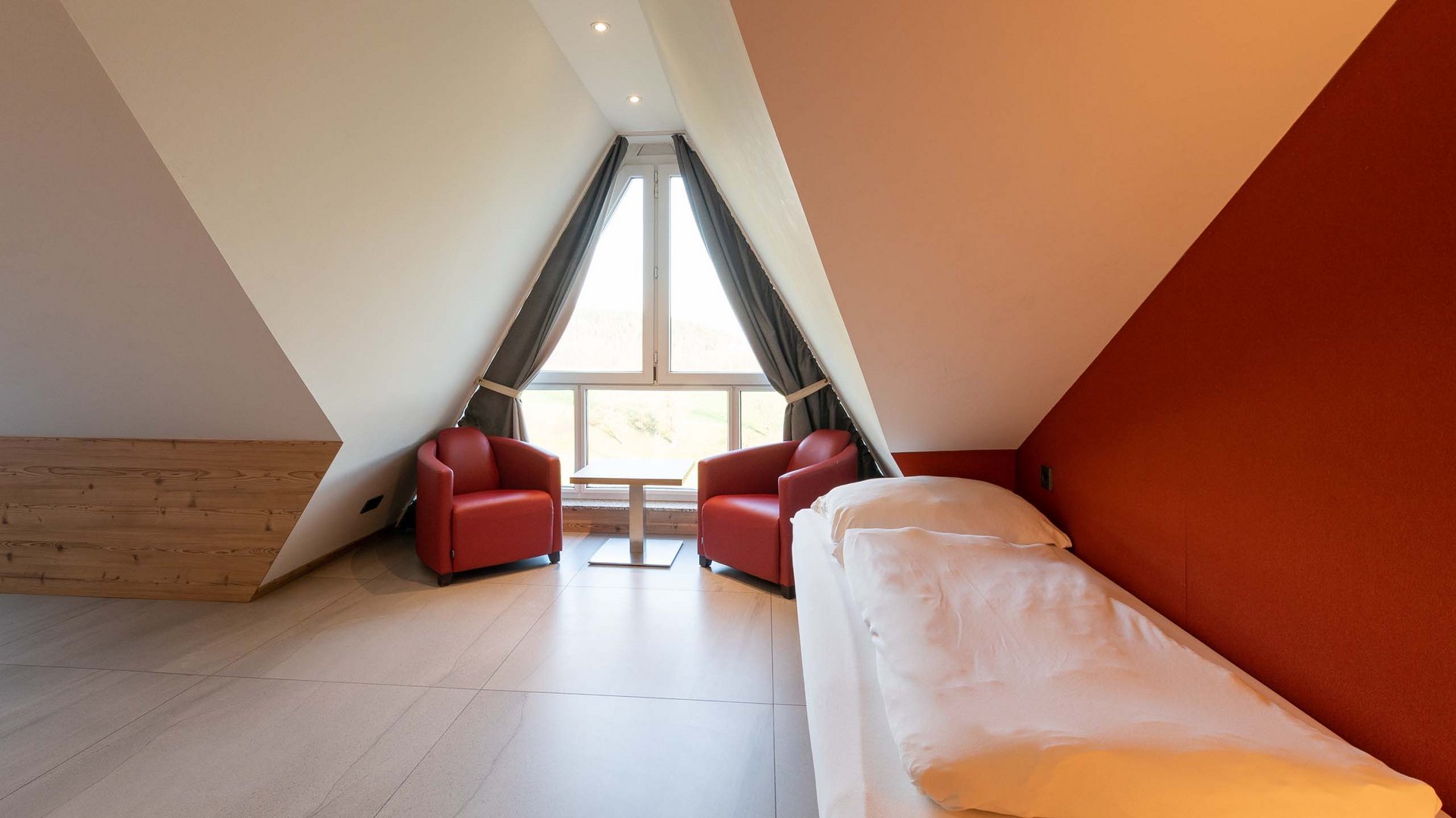 Cozy attic bedroom with two red armchairs and a single bed