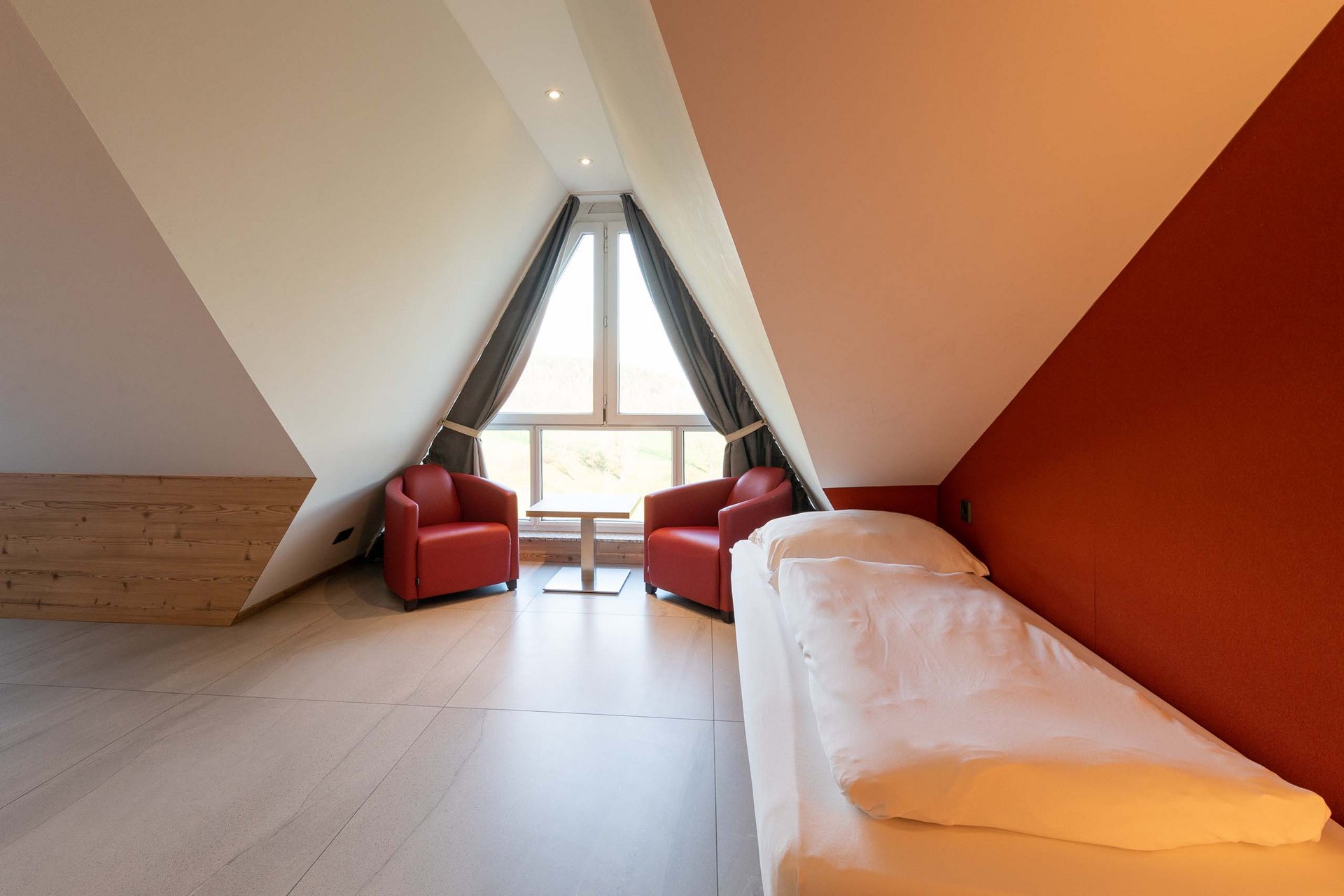 Cozy attic bedroom with two red armchairs and a single bed