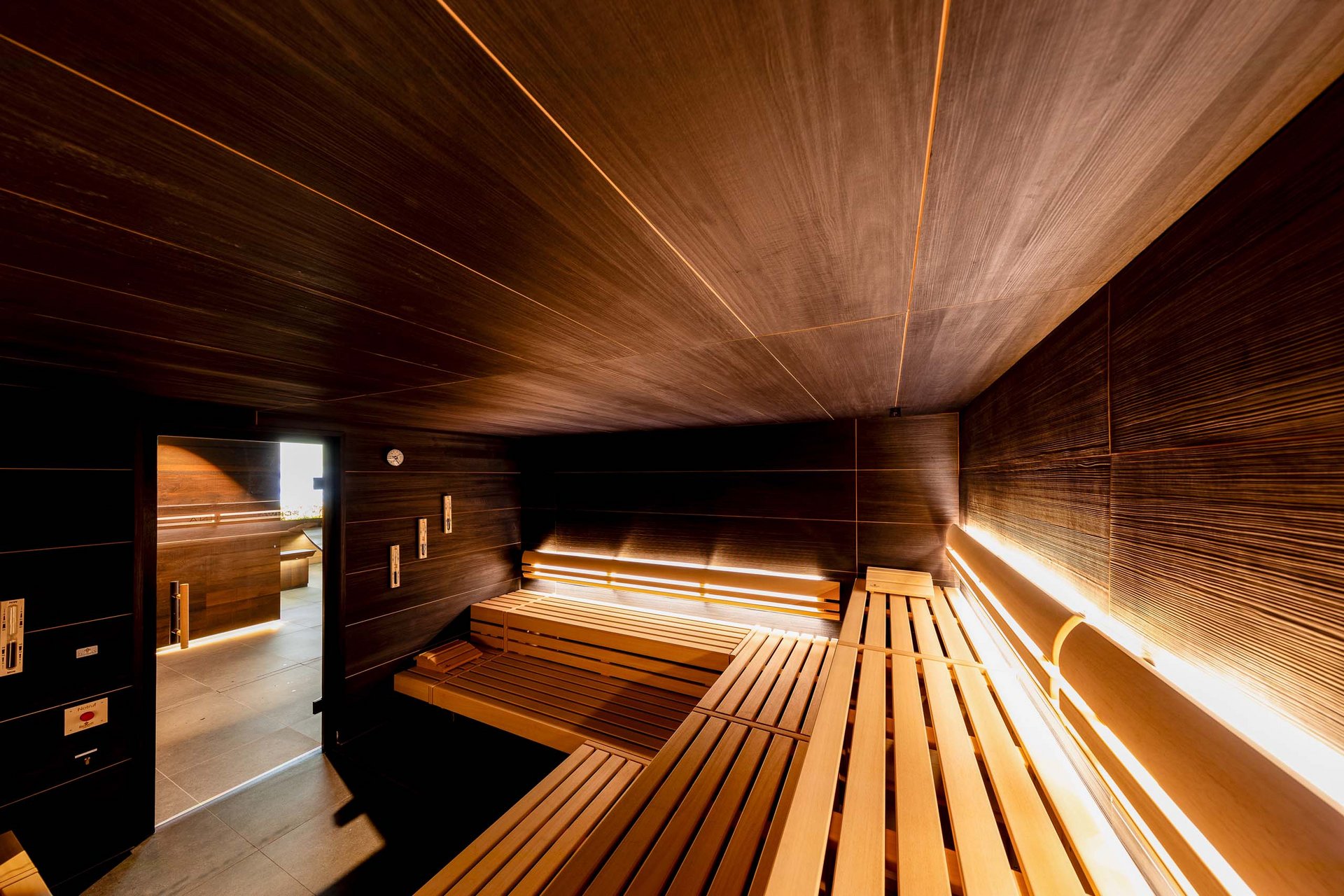 Moderner Holzsauna innen mit warmem Licht und Blick zur Tür
