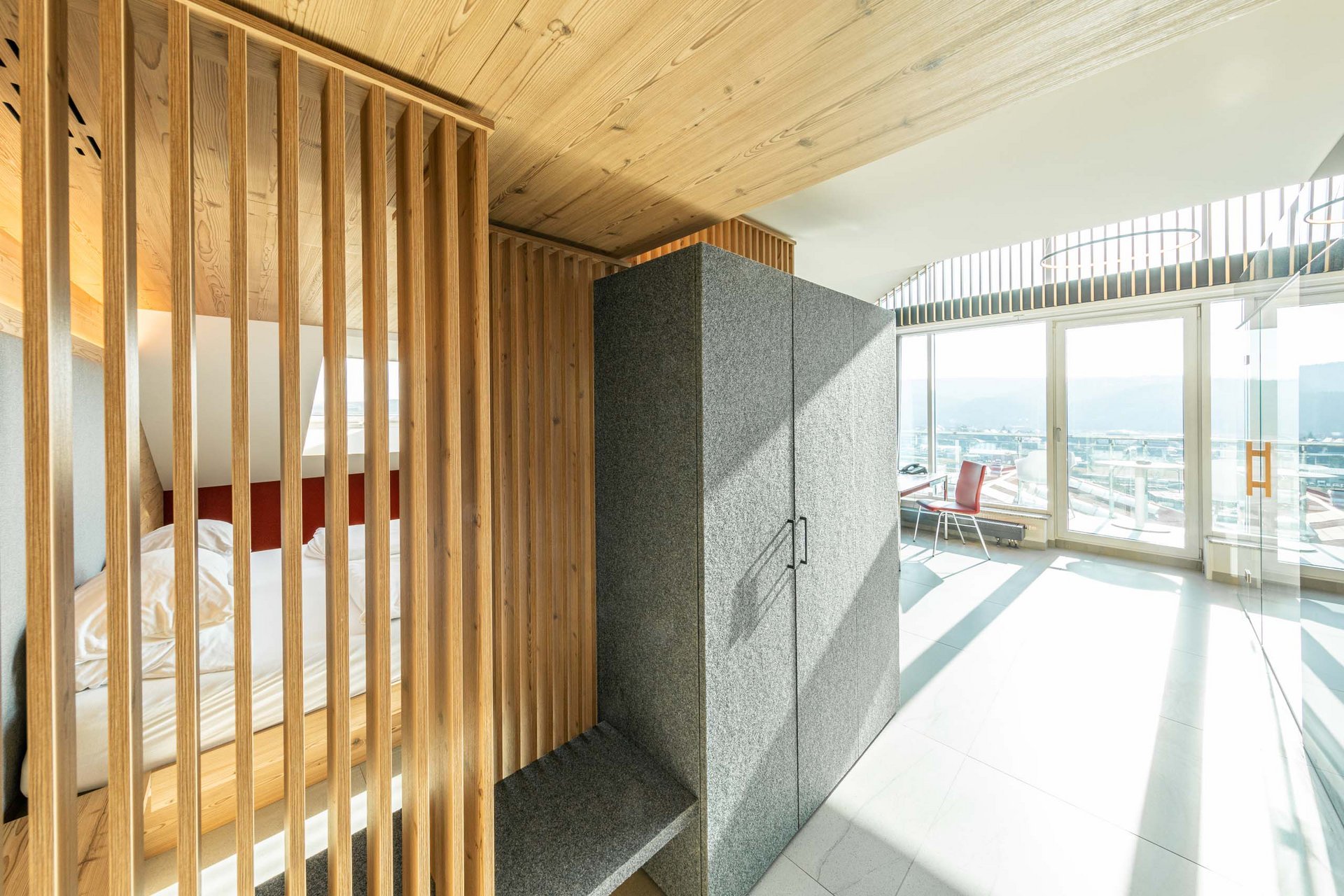 Modernes Zimmer mit Holzakzenten, grauem Schrank und großer Fensterfront