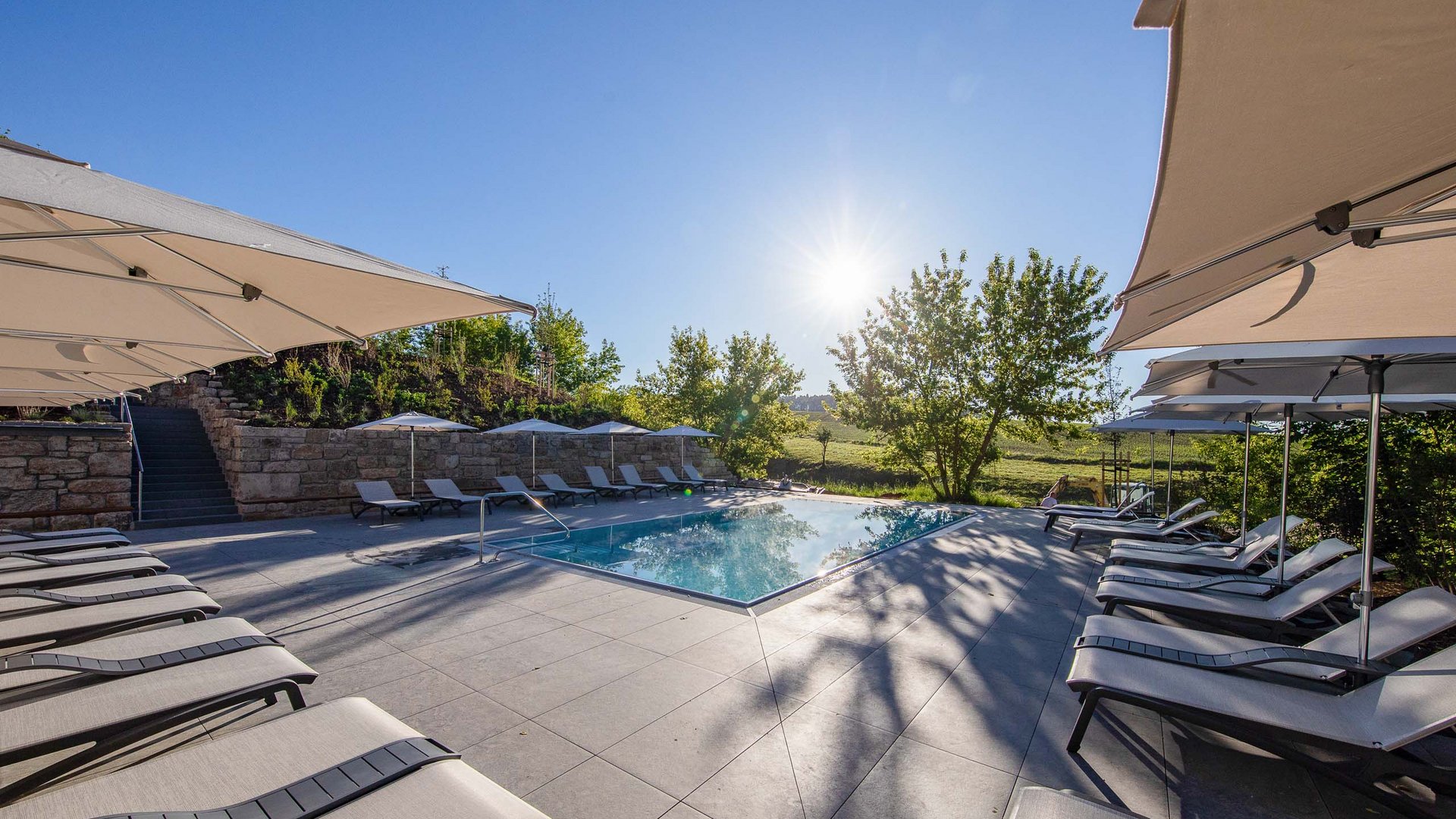 Pool with lounge chairs and umbrellas under sunny blue sky