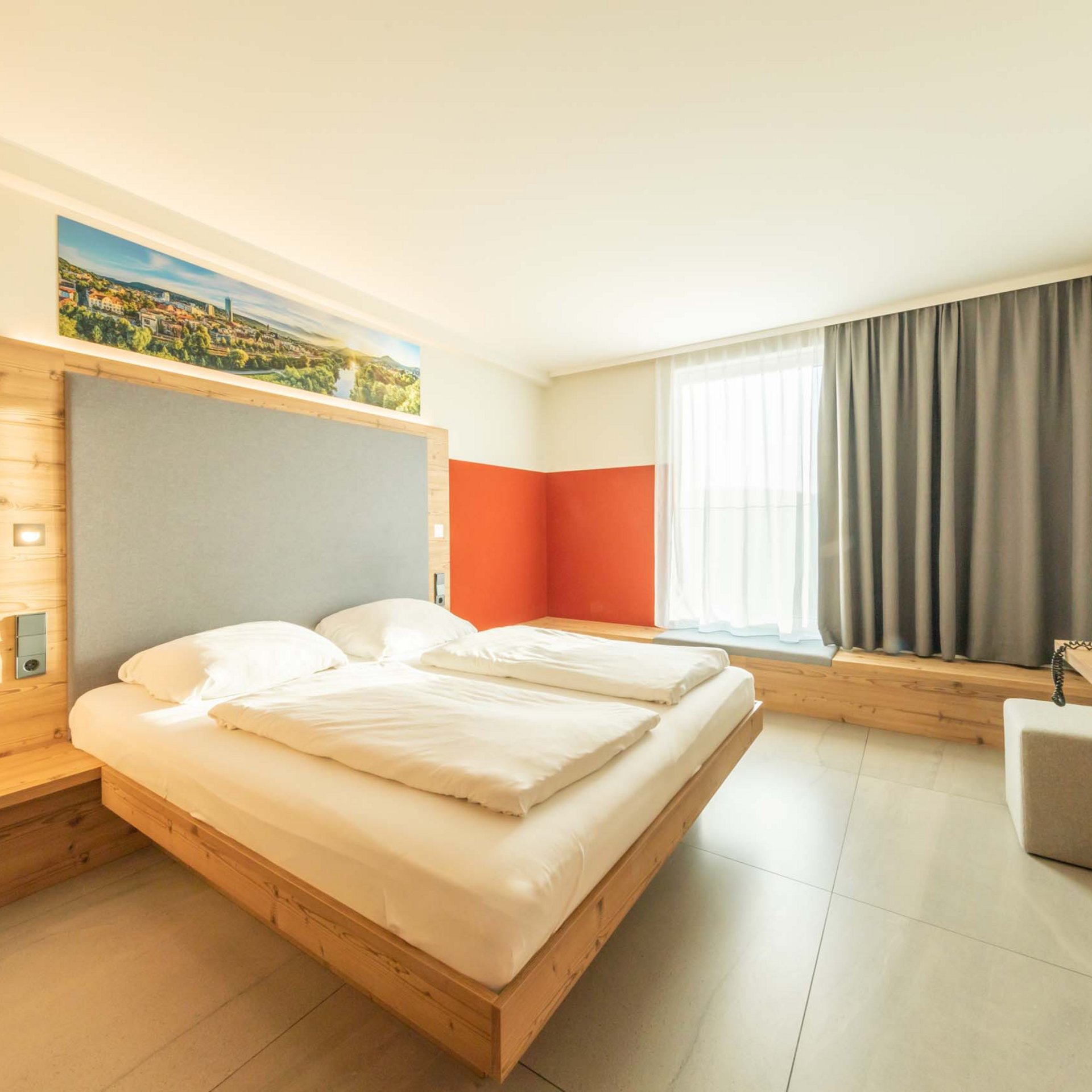 Helles modernes Hotelzimmer mit Doppelbett, großem Fenster und TV