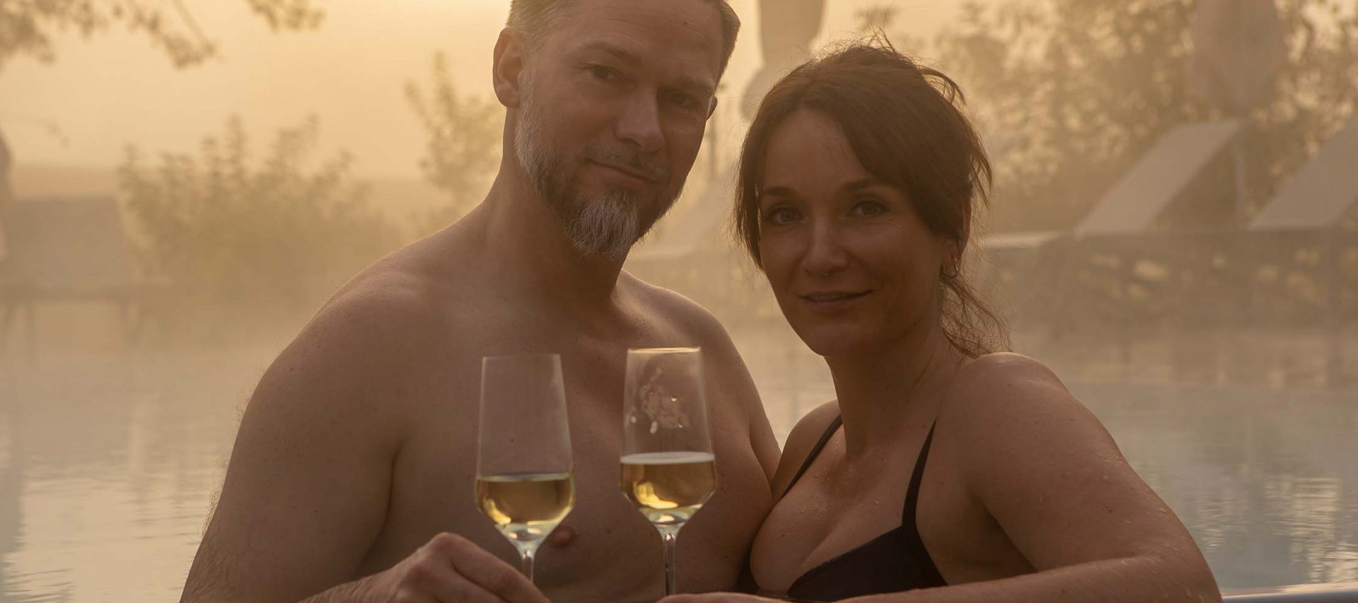 Day Spa in Jena: ein Tag nur für Sie Paar im Pool mit Gläsern Weißwein bei Sonnenuntergang