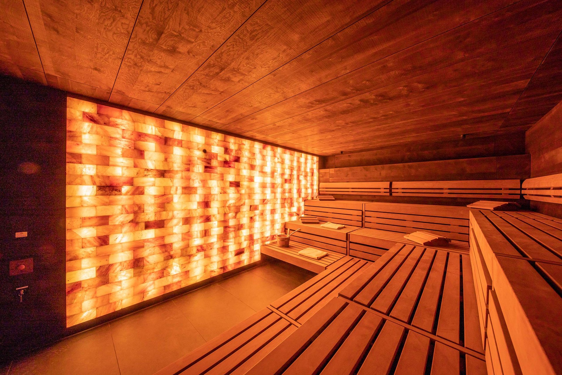 Innenansicht einer modernen Sauna mit Holzverkleidung und beleuchteter Salzsteinwand