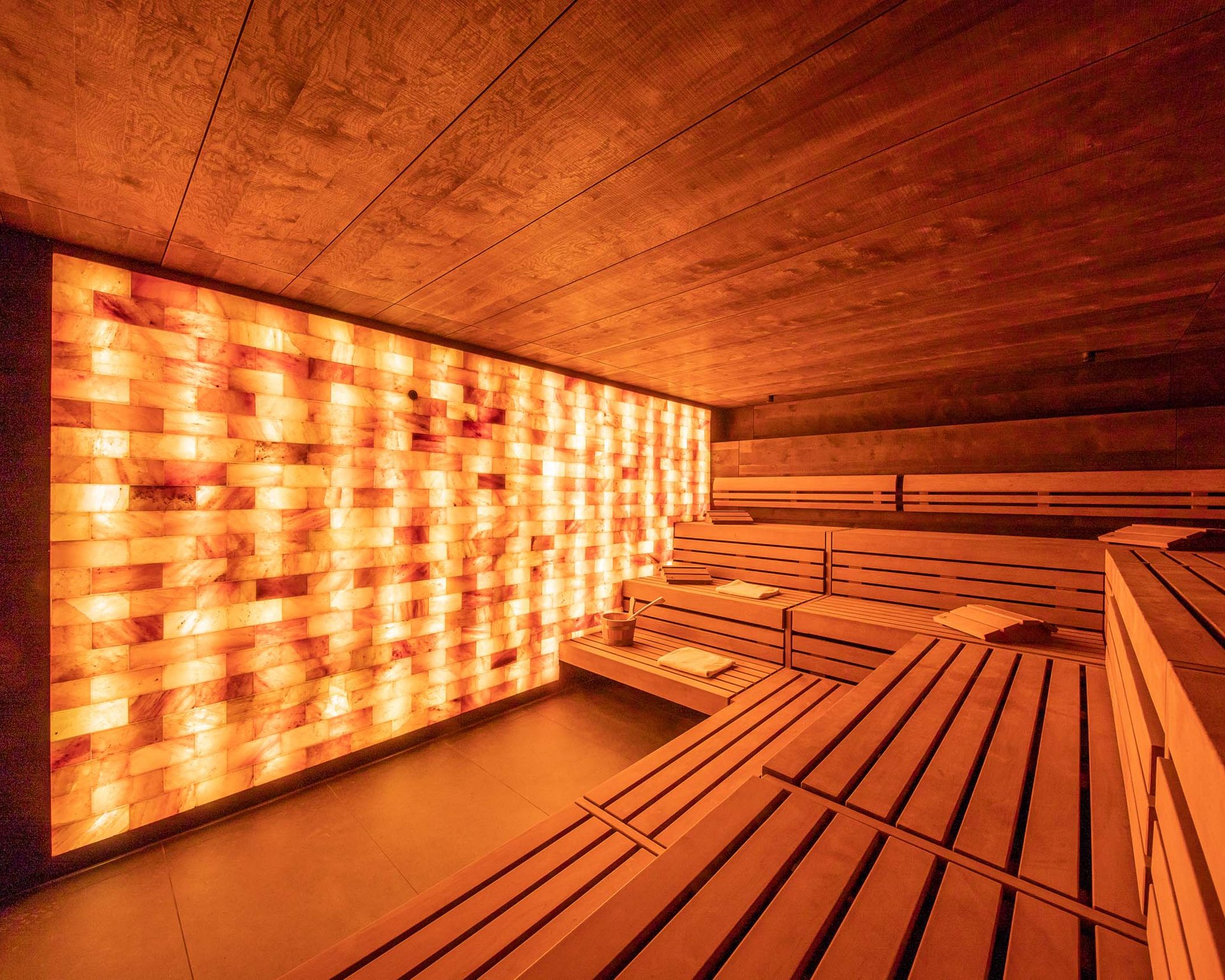 Innenansicht einer modernen Sauna mit Holzverkleidung und beleuchteter Salzsteinwand