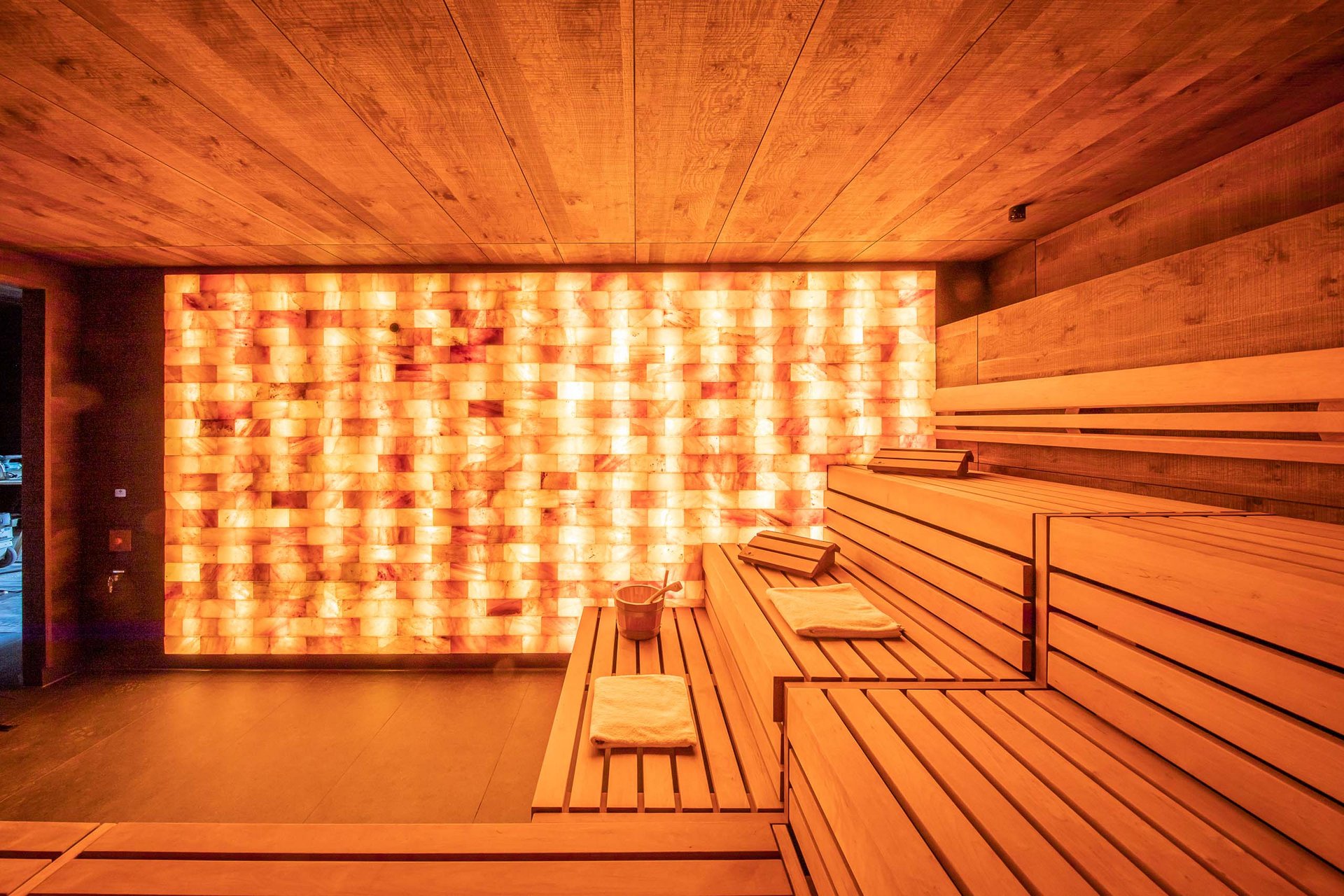 Sauna mit Holzinterieur und beleuchteter Salzsteinwand