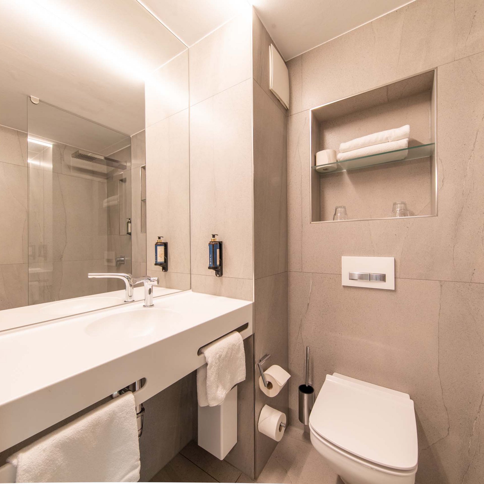 Moderne Hotelbadezimmer mit Waschbecken, WC und Handtüchern