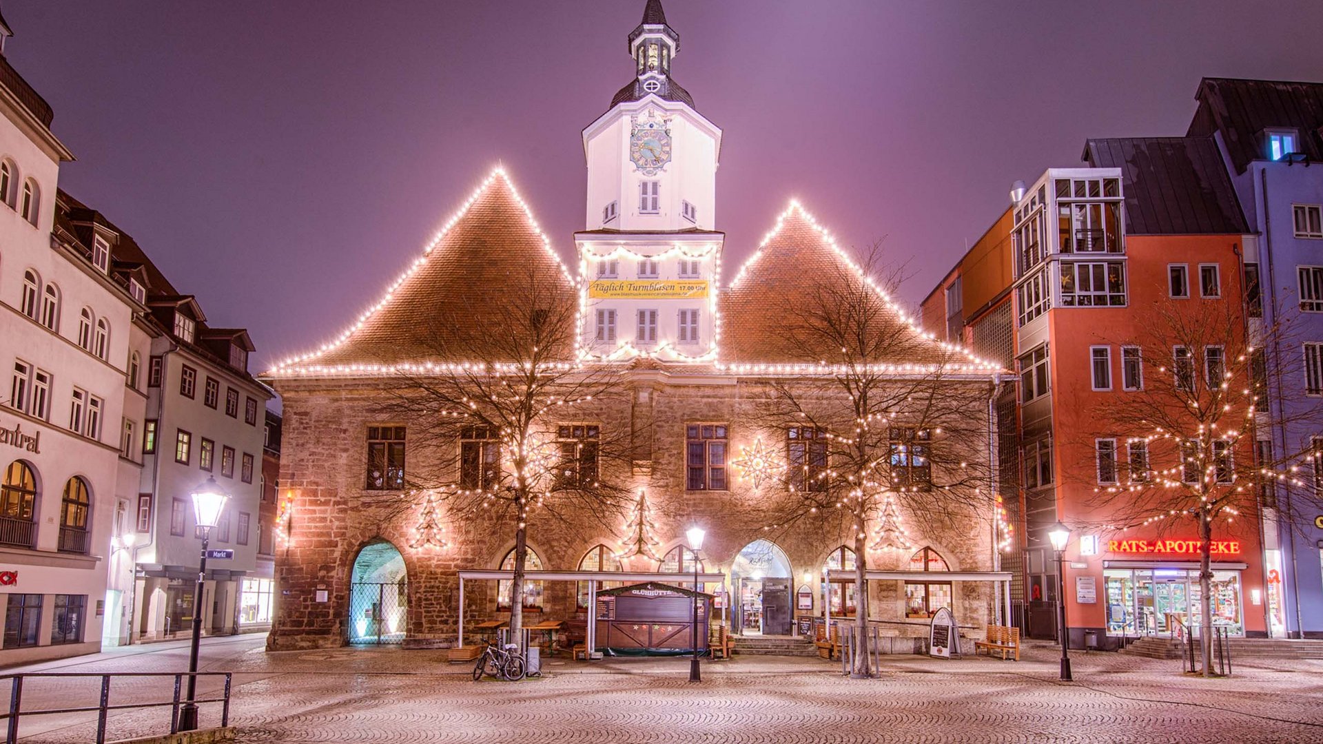 Illuminated historic town hall at night on lively market square