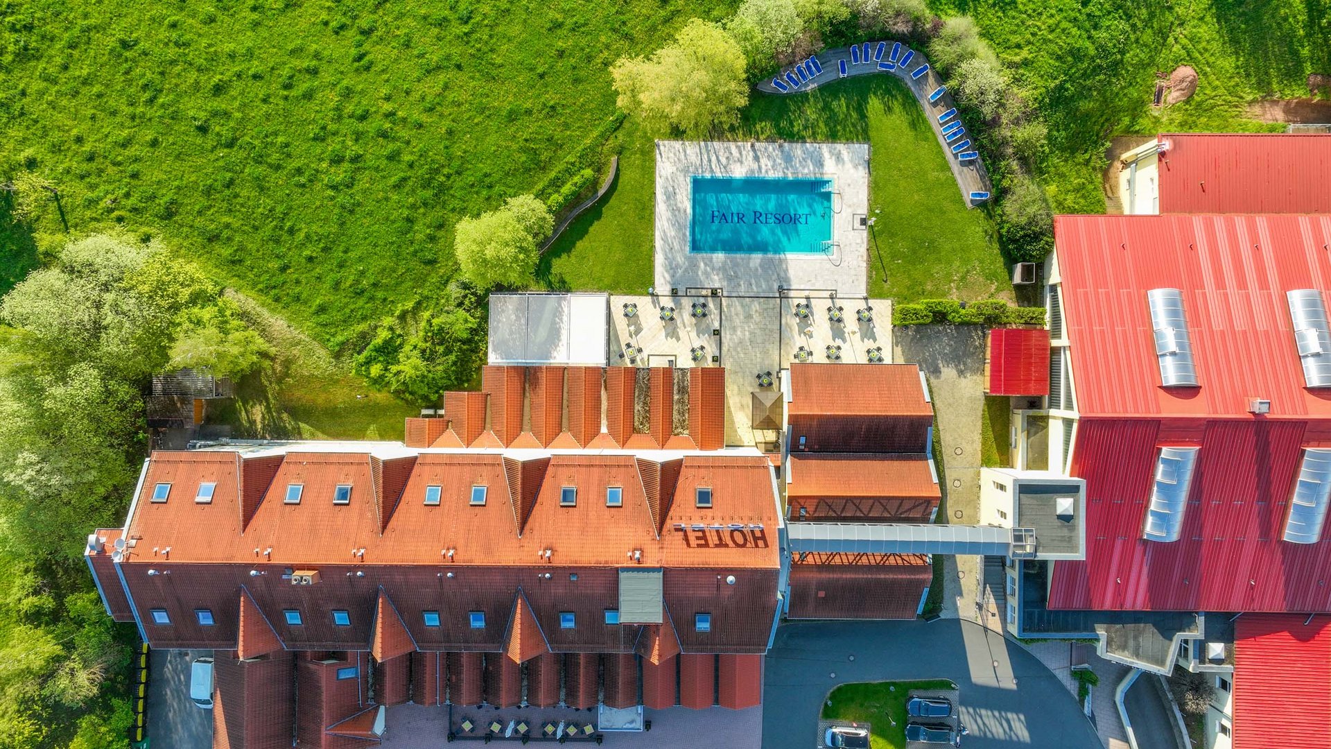 Aerial view of a hotel with swimming pool and green lawn