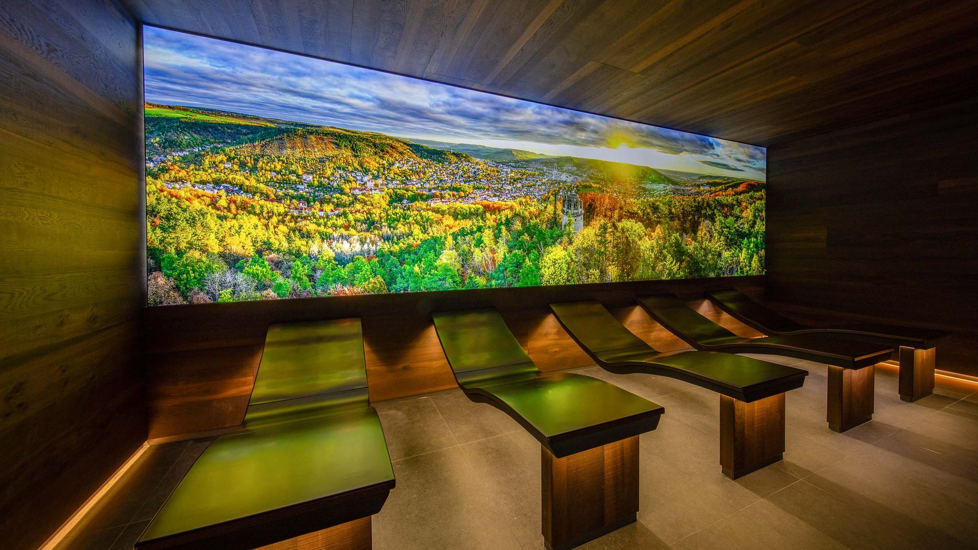 Relaxation room with lounge chairs and large wall image of autumn forest