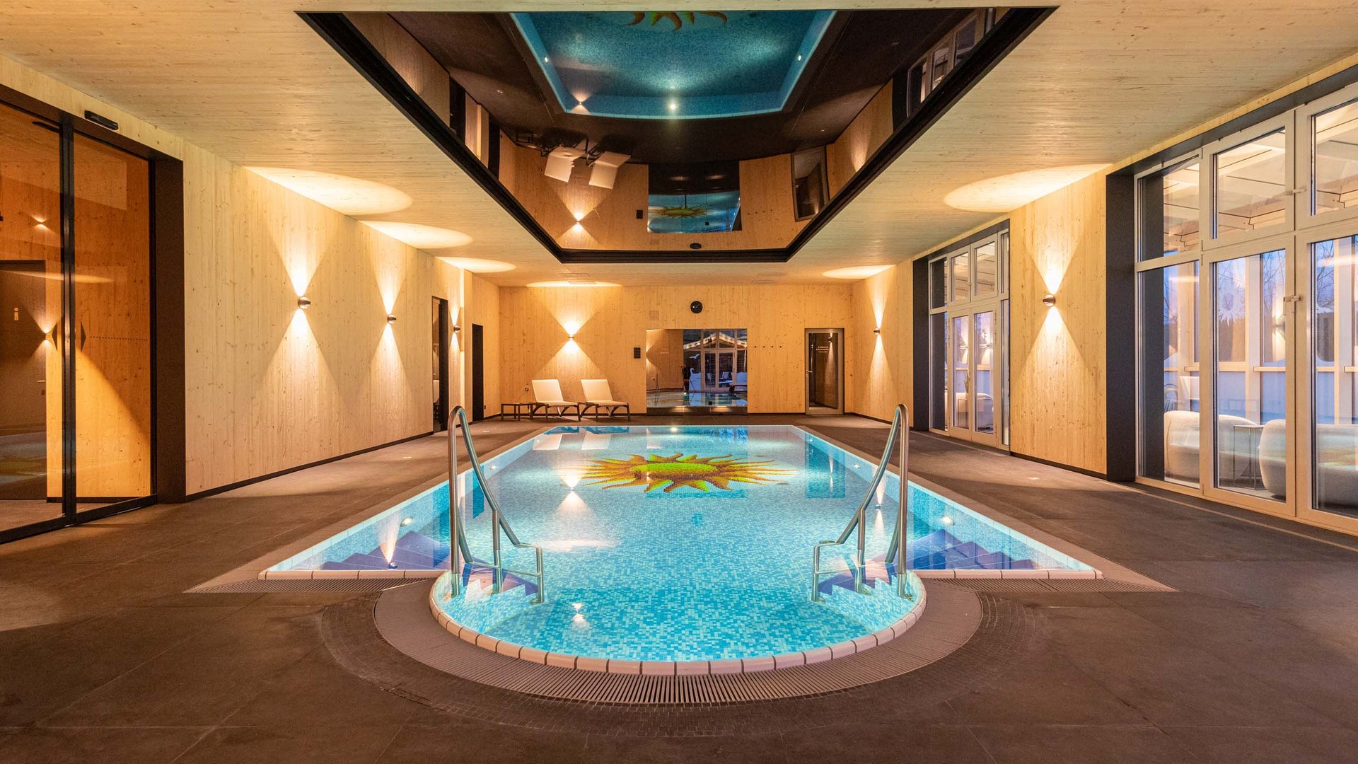 Indoor pool with sun design, wood paneling, and lounge chairs