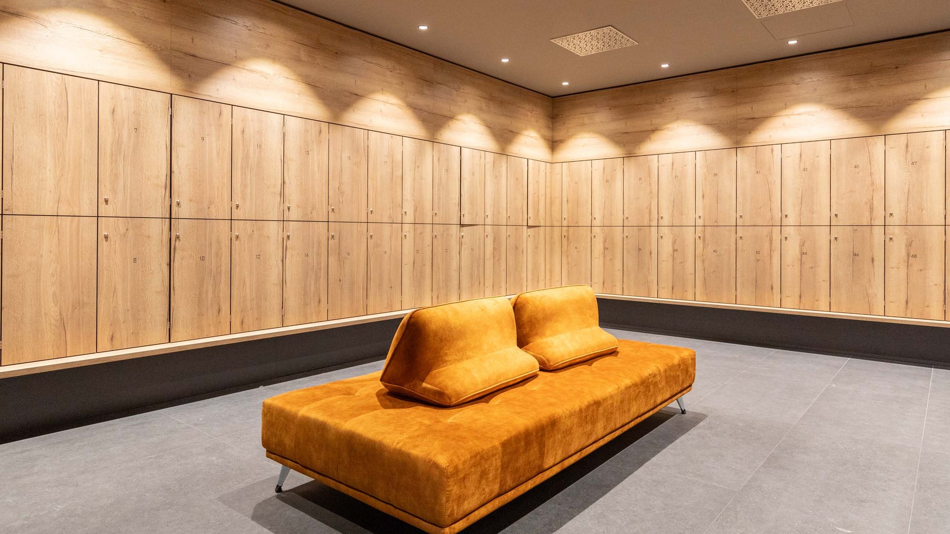 Modern locker room with wooden lockers and an orange bench in the center