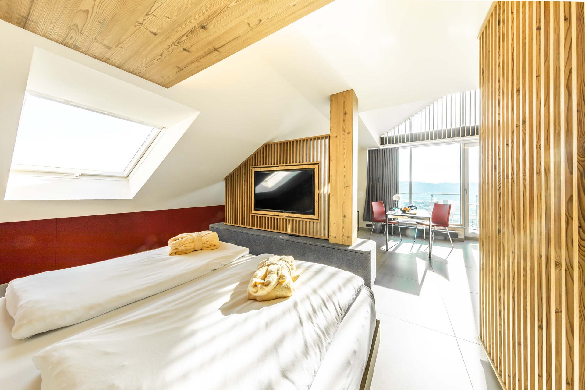 Helles Hotelzimmer mit Doppelbett, Fernseher und Balkon mit Aussicht
