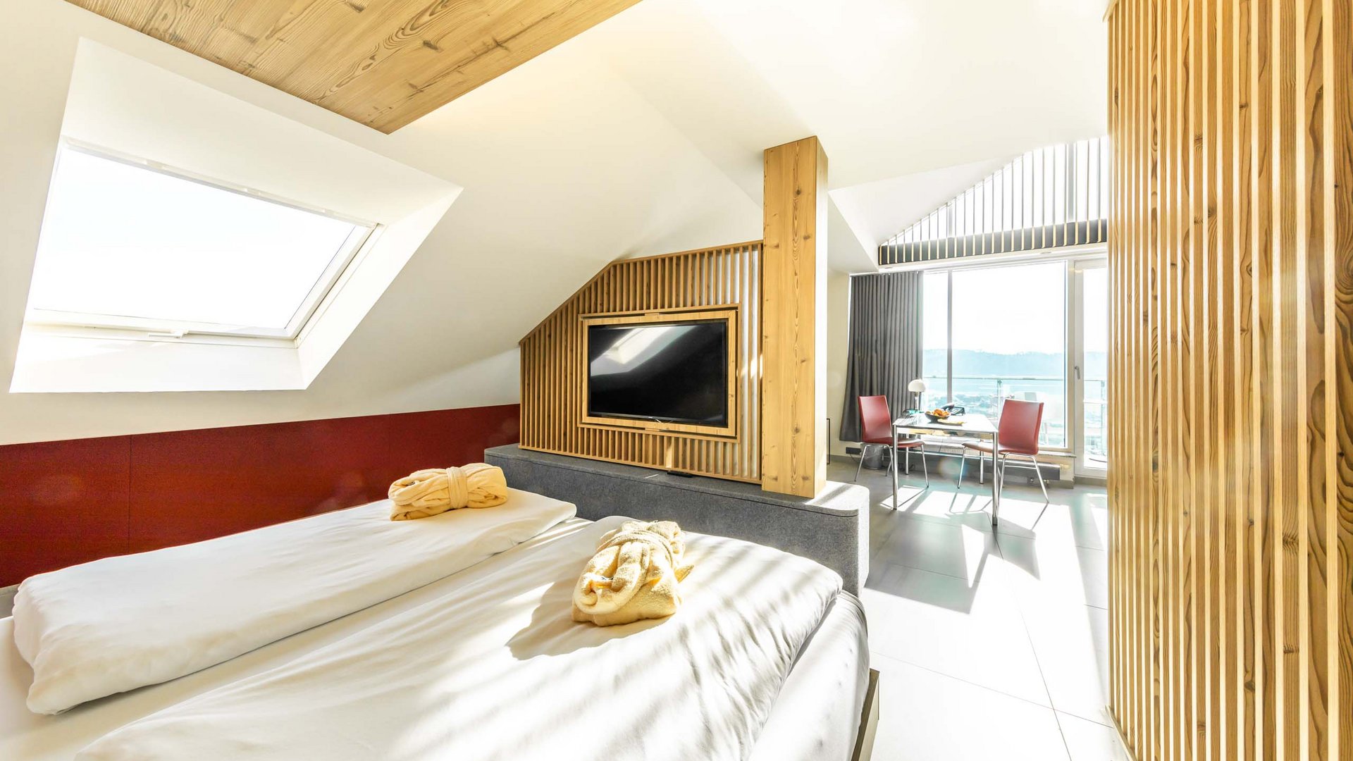 Bright hotel room with double bed, TV, and balcony with a view
